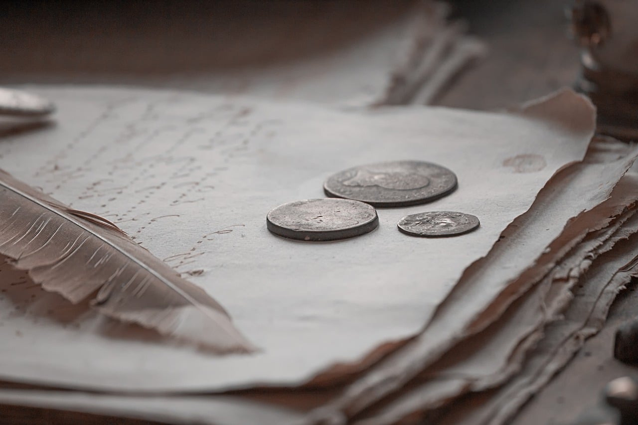 papier avec de l'argent et une plume posés dessus