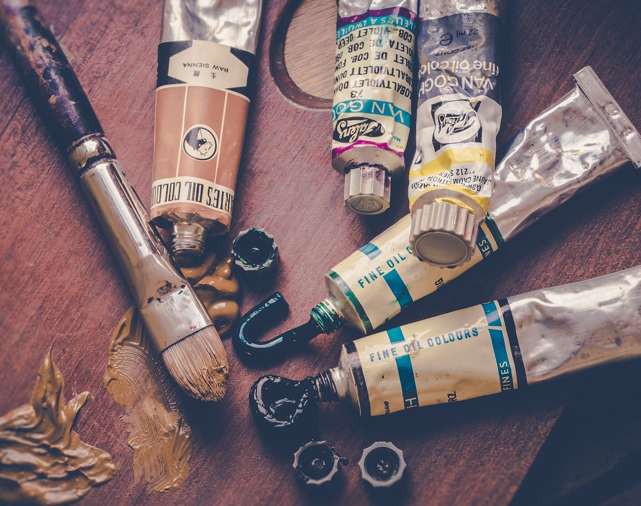 Conception et impression des invitations en papier ensemencé 1 tubes de peinture de plusieurs couleurs et un pinceau posés sur une table